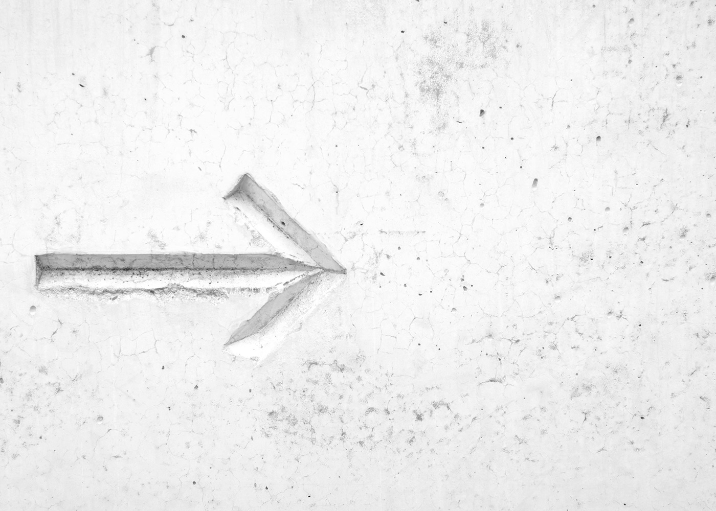 An arrow pointing left to right carved into a white stone background.