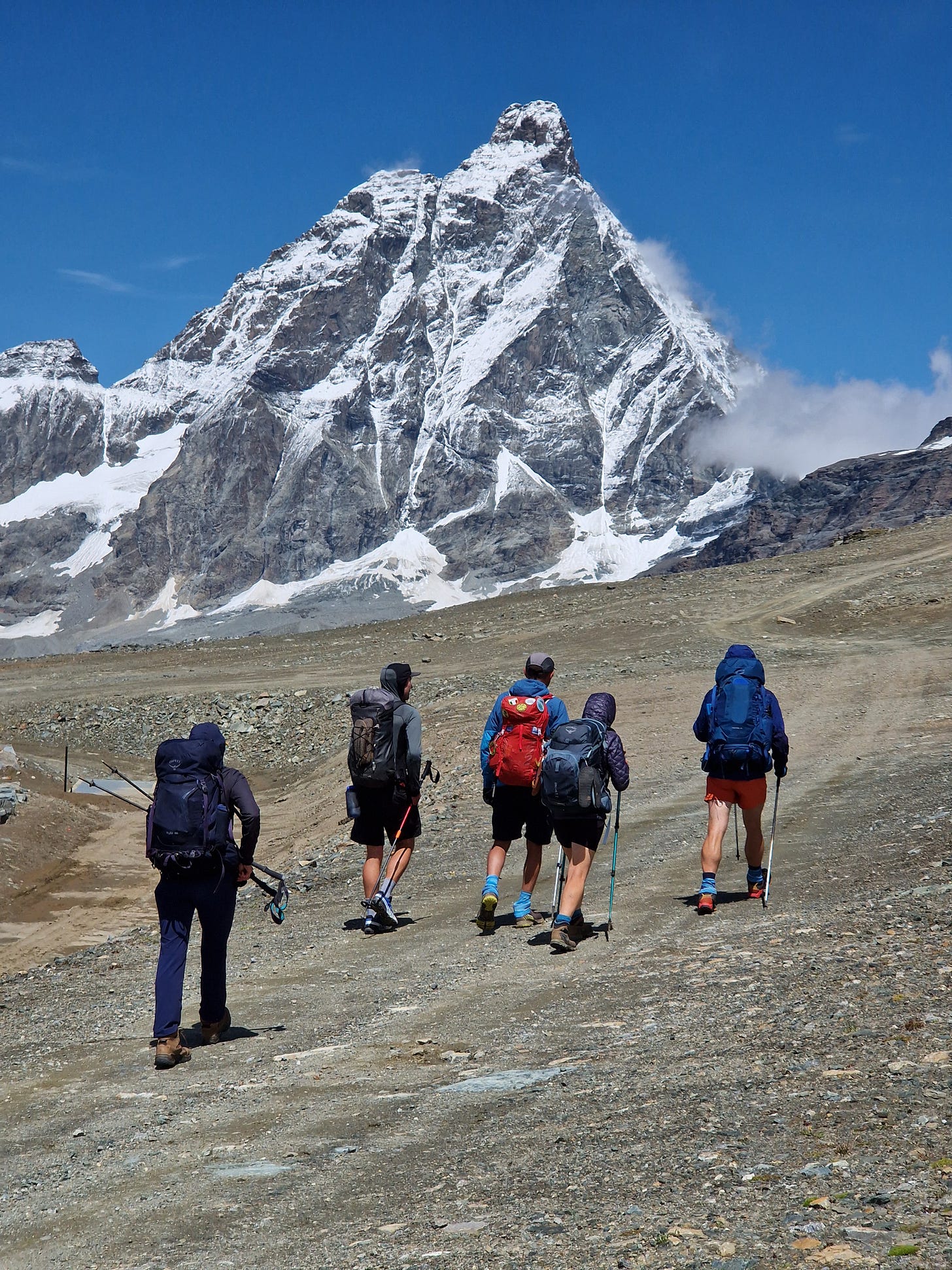 Five hikers walking on wide path with The Matterhorn towering in background Five hikers walking on wide path with The Matterhorn towering in background