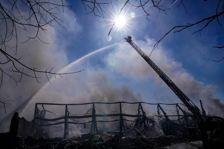 Arc of water from a ladder truck sprays on the smoldering fire