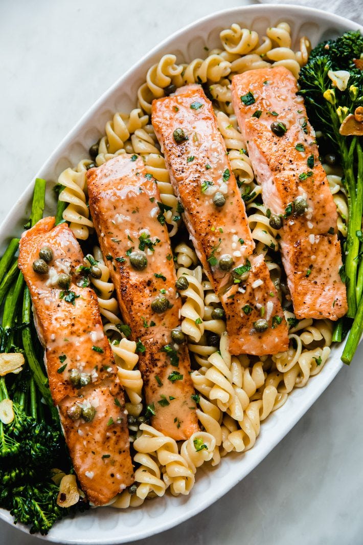 salmon piccata on platter with fusilli pasta and broccolini
