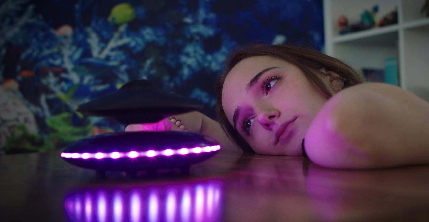A young woman stares in daydream at an LED UFO toy