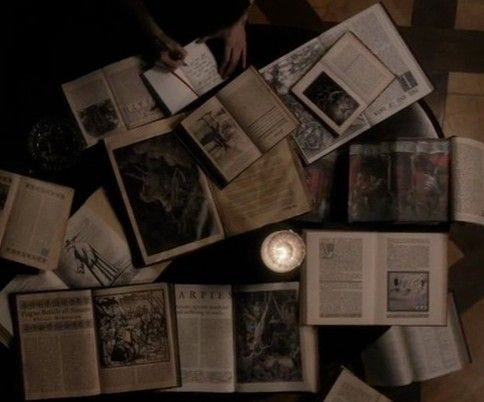 This may contain: an overhead view of several open books on a table with a candle in the middle