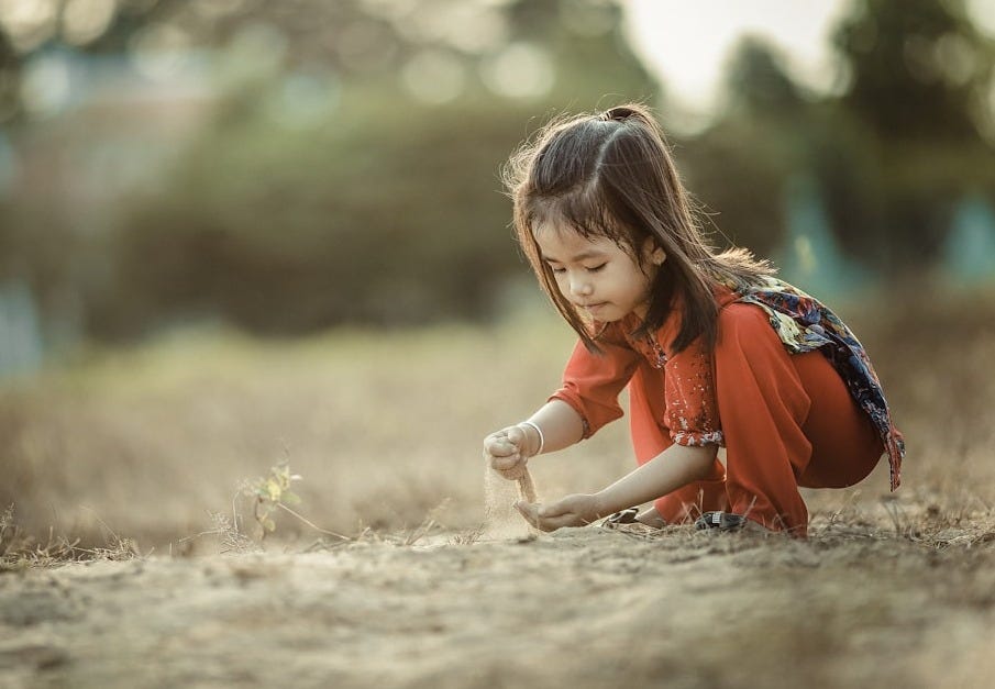 girl playing sand during daytime