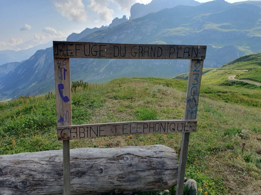 Une image de montagne avec un cadre en bois sur lequel est écrit "refuge gradn plan, cabine téléphonique, 