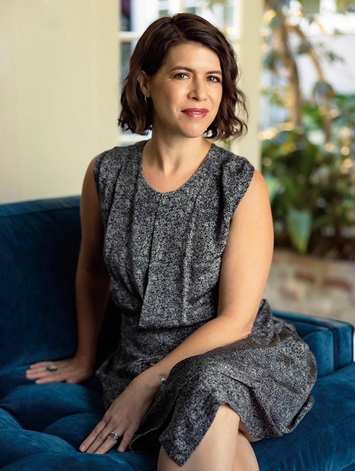 A woman sits and smiles at the camera