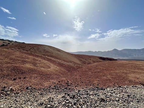 The raw volcanic terrain of Montana Blanca, rocky hills rising on both sides of the empty hiking path.