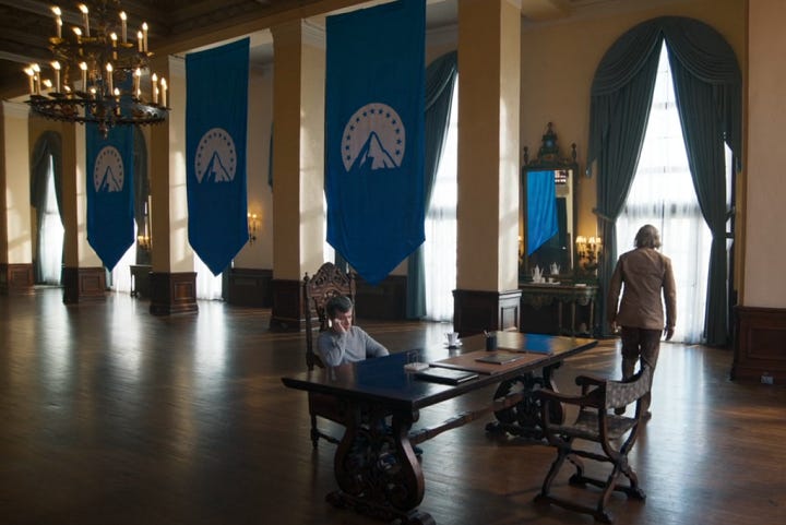 Image one: a room with blue Paramount flags draping down the windows, and a man dressed like a WWII Nazi. Image 2: Paramount's security forces wearing the Paramount logo in place of a Swastika armband.