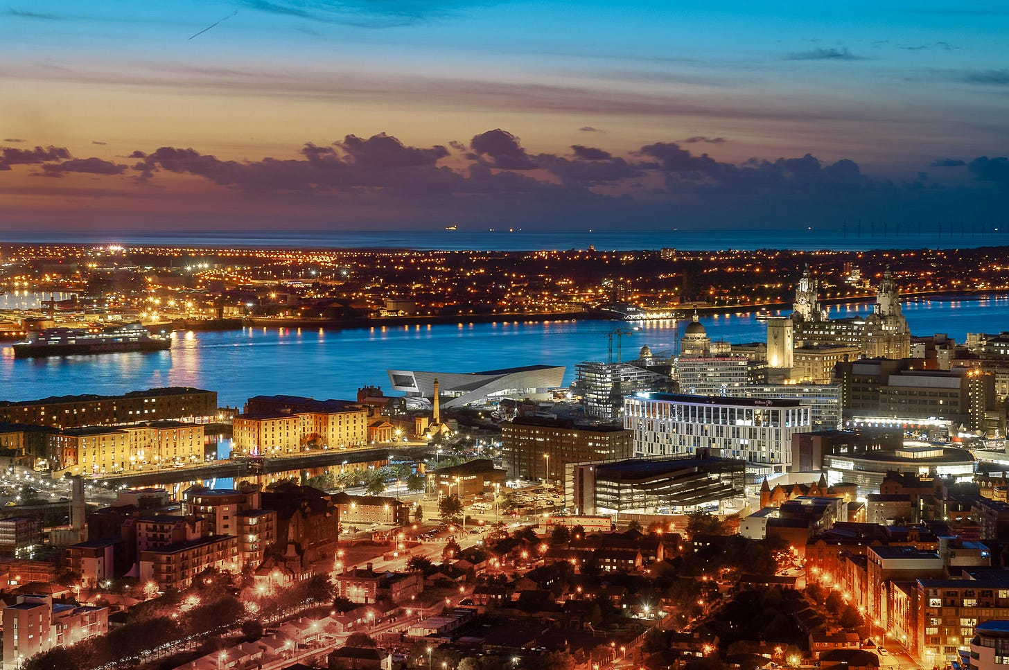 Dusk. The lights of the city are on. This is the Liverpool waterfront from the Royal Albert Dock to Liver Building including the Museum of Liverpool and the 3 Graces.