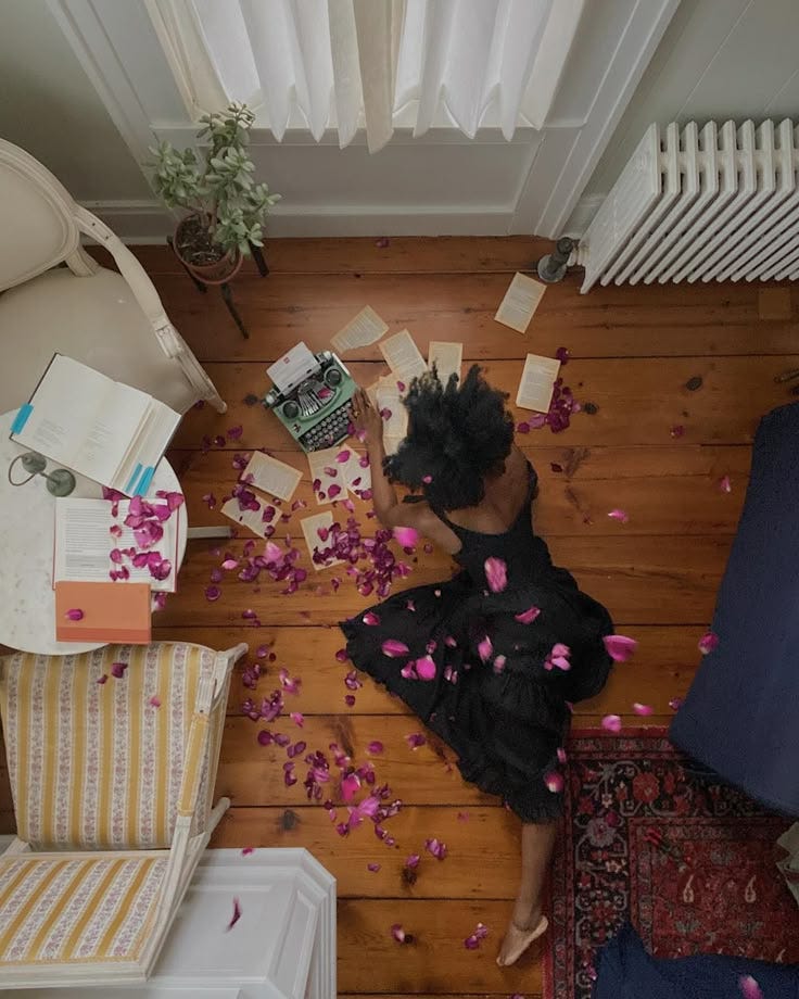 This may contain: a woman is sitting on the floor surrounded by confetti and petals in her hair