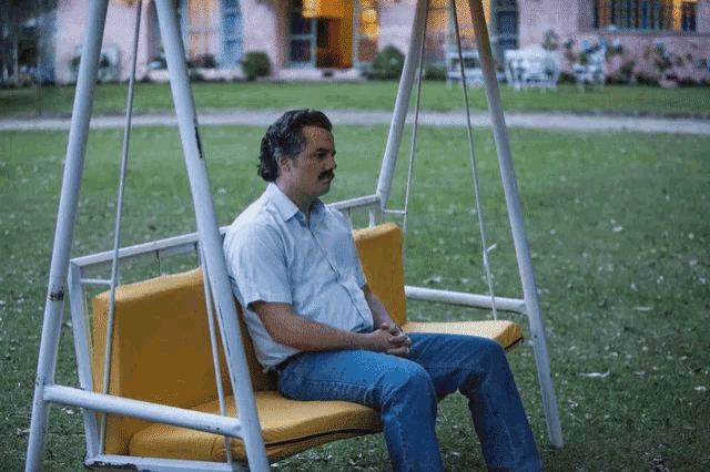 a man with a mustache sits on a yellow swing a man with a mustache sits on a yellow swing