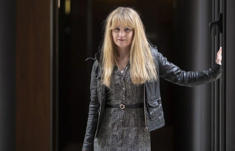 Cat Jarman posing by a door in a jacket and dress Cat Jarman posing by a door in a jacket and dress