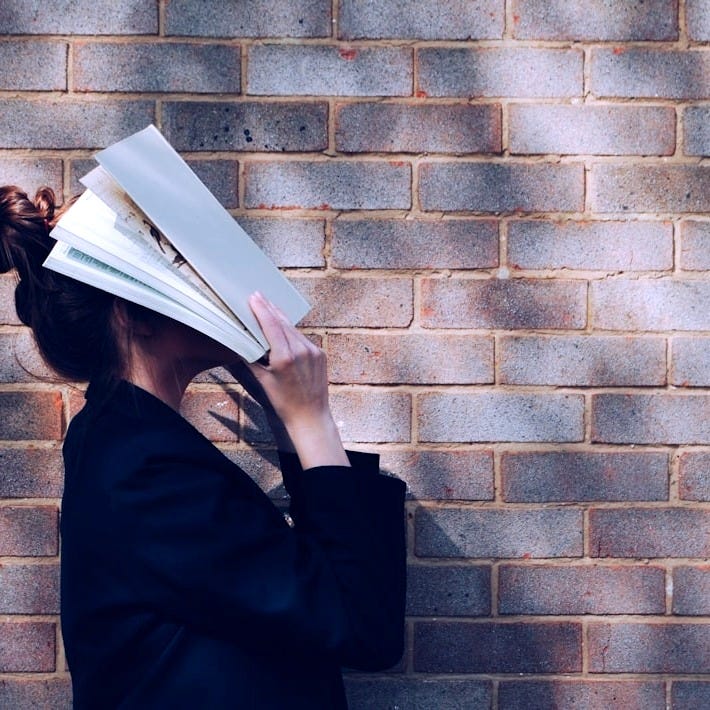 woman covering her face with white book woman covering her face with white book