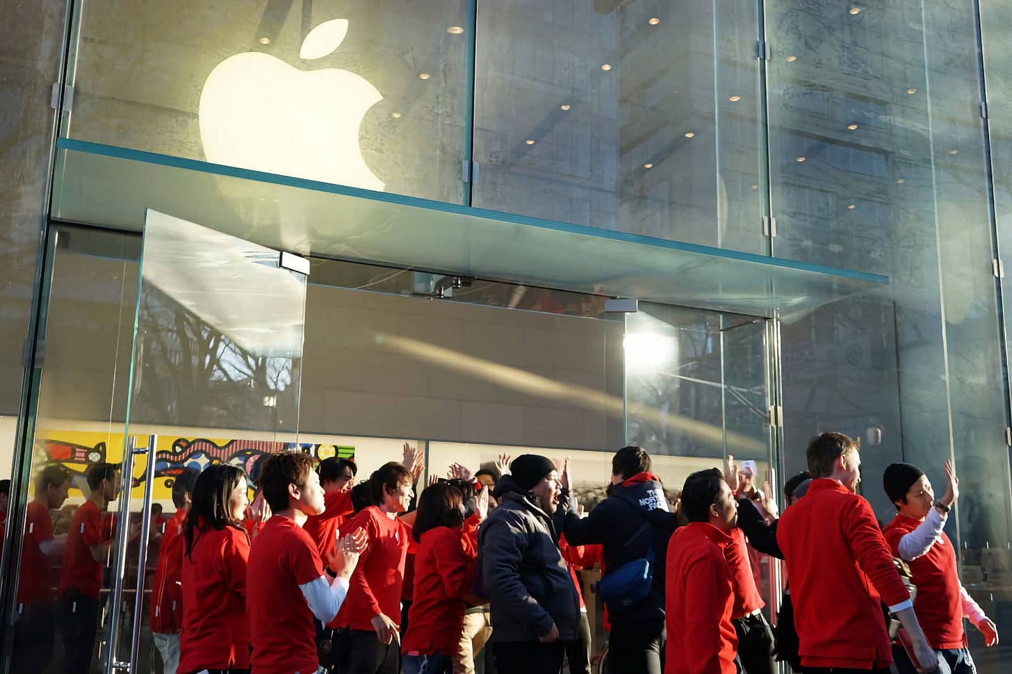 Customers and store employees cheer outside Apple Omotesando. Customers and store employees cheer outside Apple Omotesando.