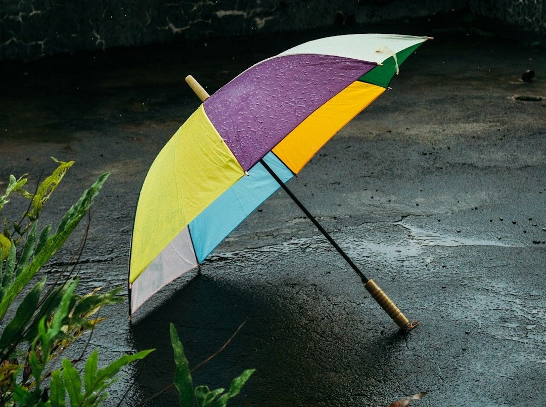 a colorful umbrella sitting on top of a wet ground