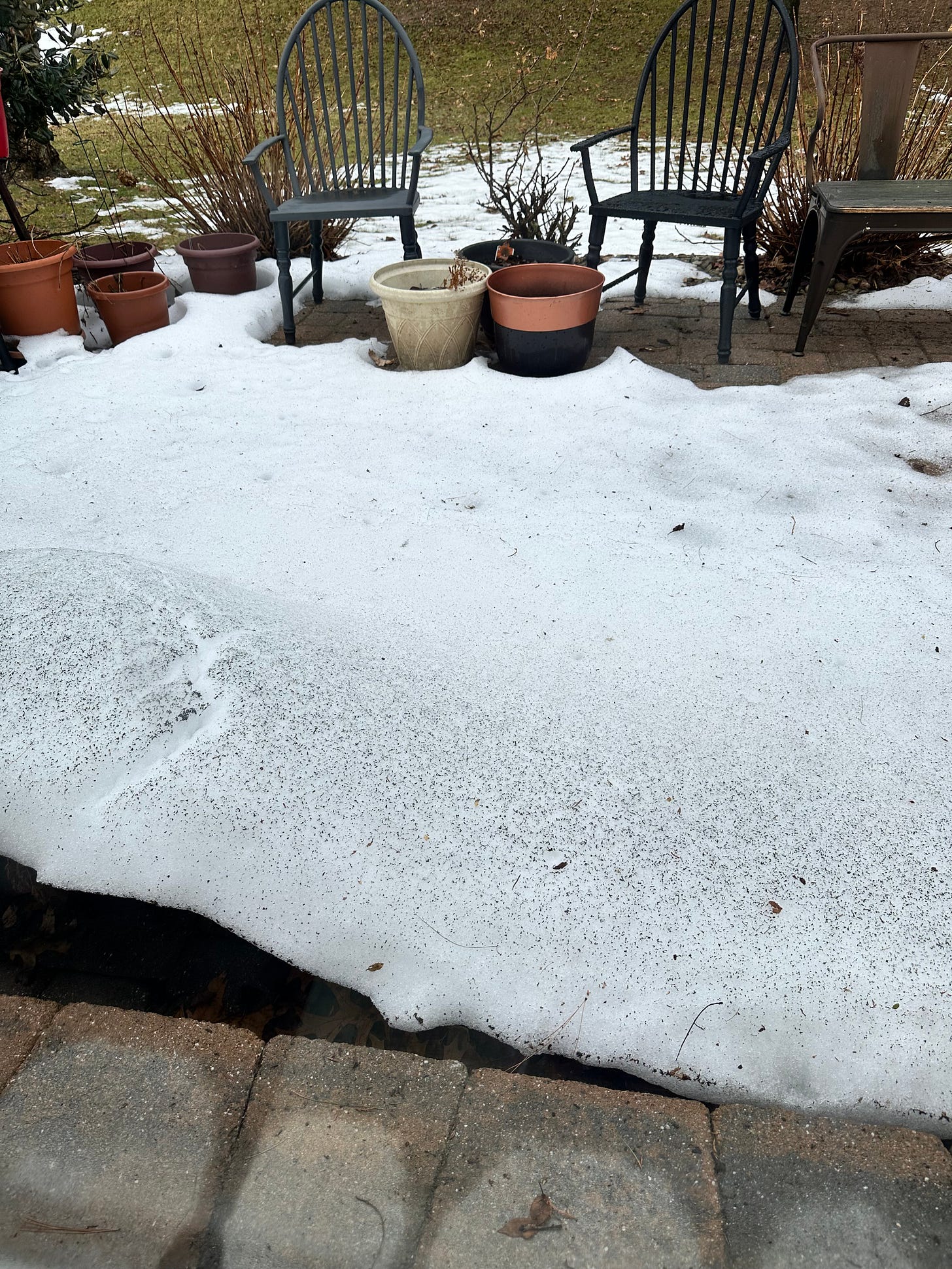 patio with chairs, potted plants and a thick layer of snow, now melting rapidly