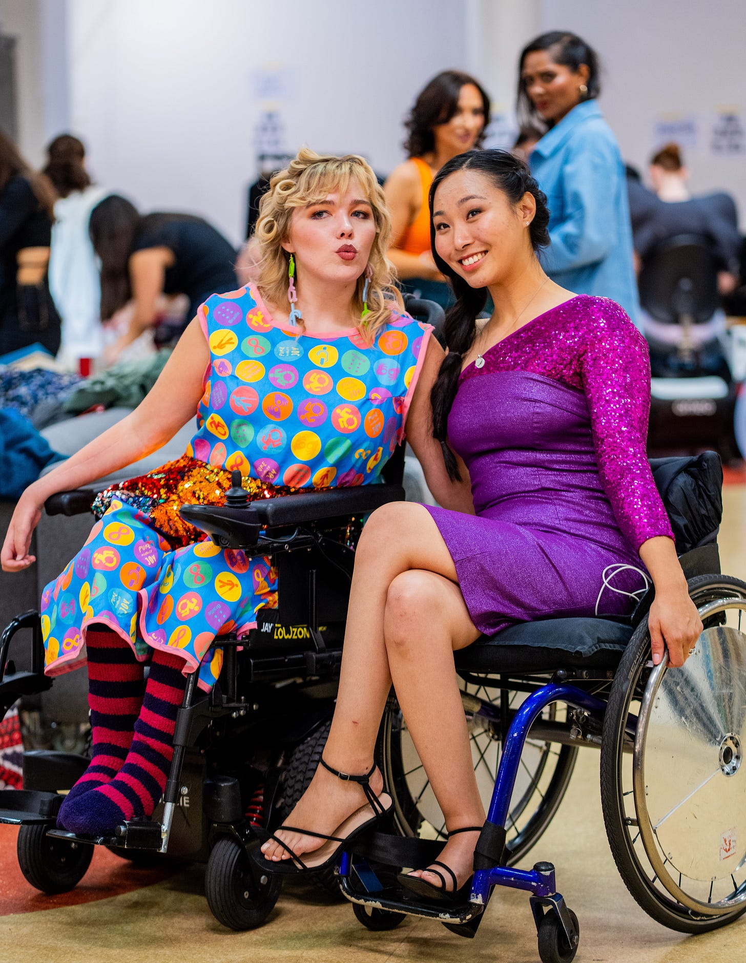 two models in wheelchairs posing for the camera backstage