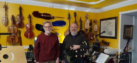 Robert et Peter, avec les même cheveux courts et gris, posent dans un appartement et devant un mur où sont exposés de nombreux instruments de musique, à cordes et à vent. Robert et Peter, avec les même cheveux courts et gris, posent dans un appartement et devant un mur où sont exposés de nombreux instruments de musique, à cordes et à vent.