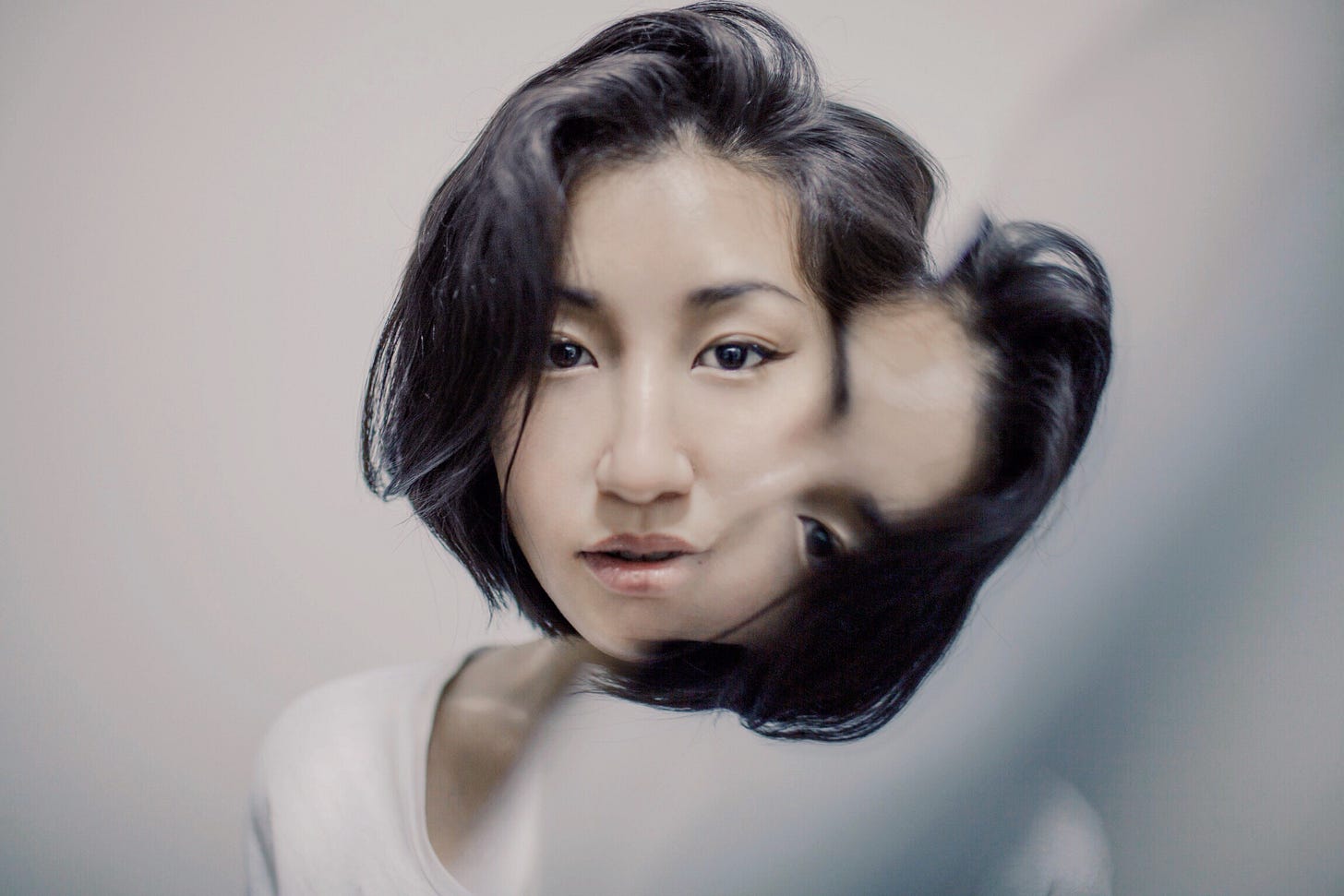 A woman in a white t-shirt and her split and warped reflection.