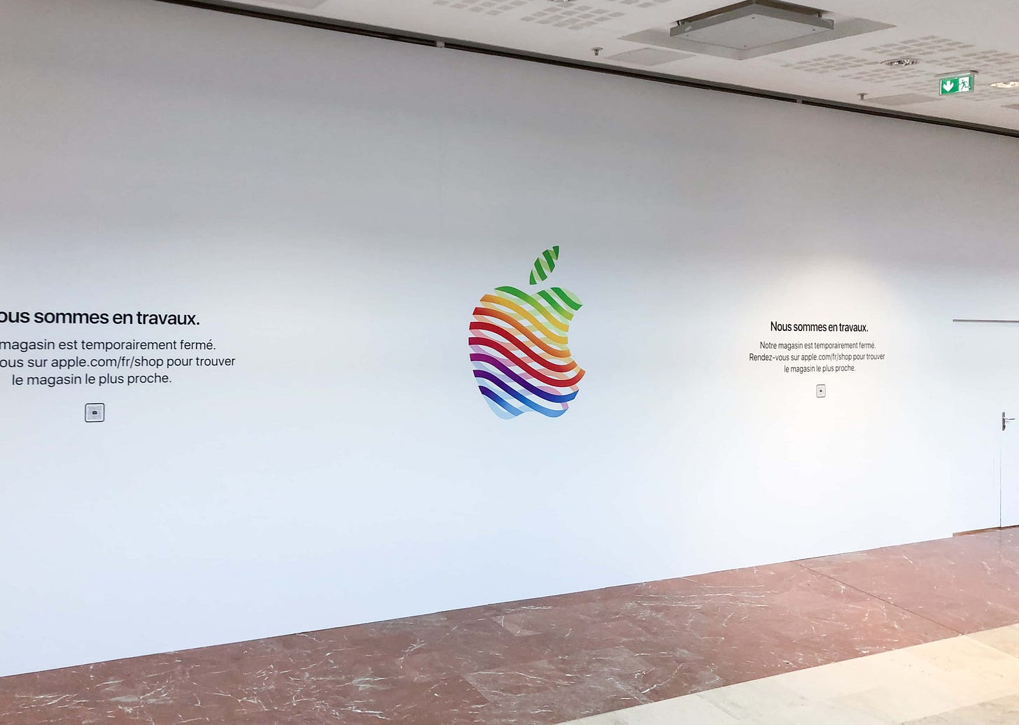 The entrance to Apple Vélizy 2 covered with white vinyl and the heritage logo. The entrance to Apple Vélizy 2 covered with white vinyl and the heritage logo.