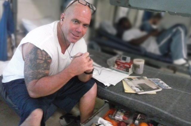 The author writing at his bunk in prison.