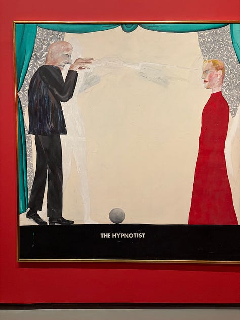 Multiple bright-colored paintings including a self-portrait of Hockney in a yellow plaid suit and big yellow glasses, the crowd viewing paintings, a mother and child in front of a bright painting of a massive tree, an annunciation painting redone in neon colors, a green lawn with sprinkler spray, a photograph of hockney working at his drawing table with his little terrier dog under the table and two paintings with raindrops hitting puddles among trees