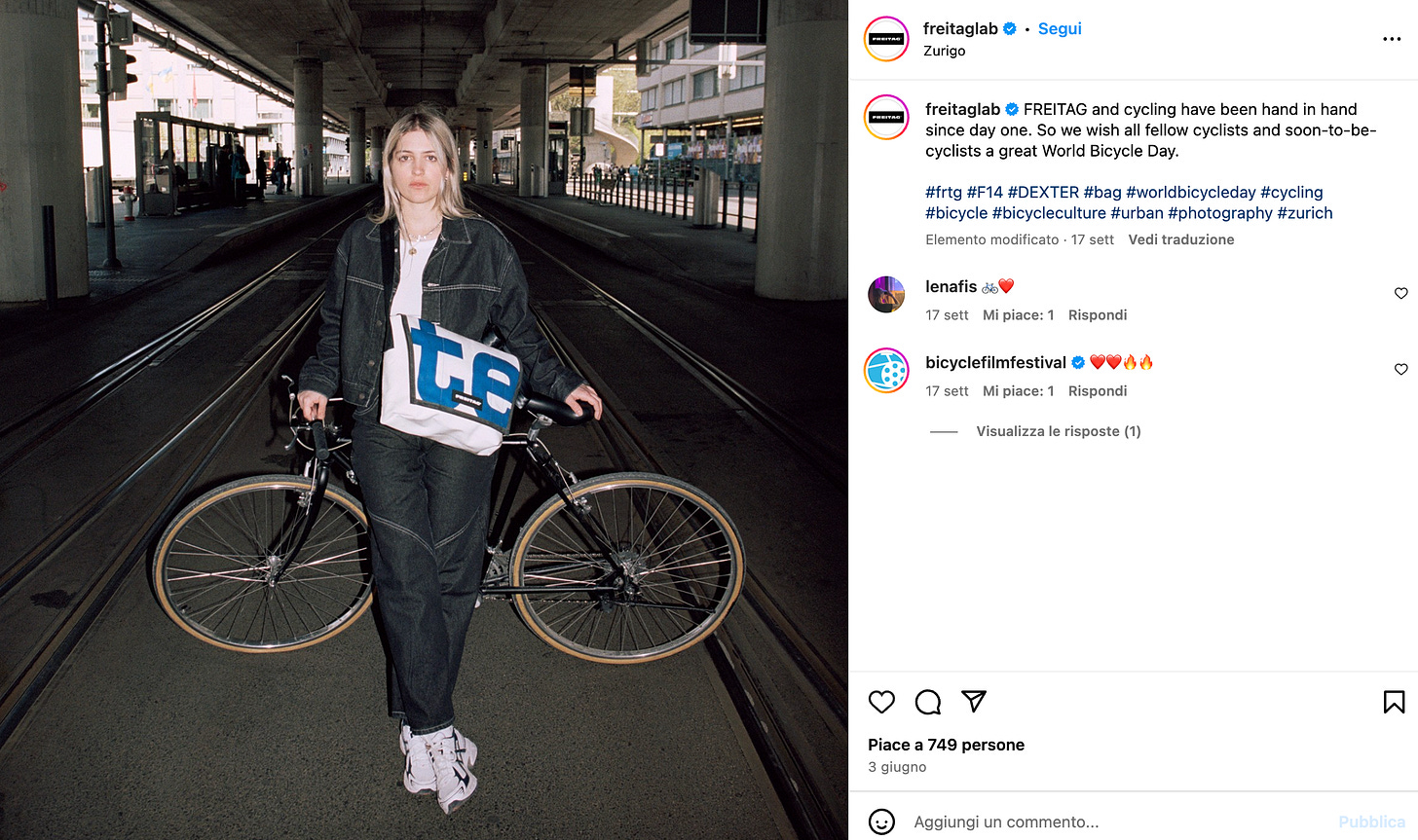 Scenario urbano, metropolitana, banchina. È giorno, una ragazza è appoggiata alla sua bici con una grande tracolla FREITAG che le copre quasi tutto il busto per quanto è grande. È bionda, spettinata, imbronciata e bellissima. Lo scatto sembra rubato dallo smartphone di qualcuno.