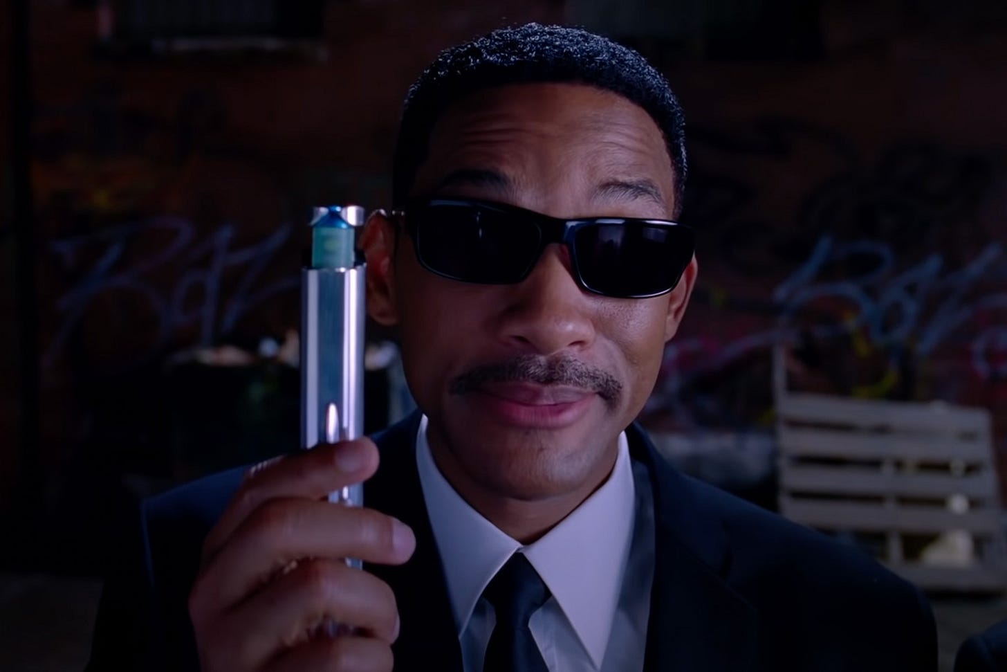 Agent J (Will Smith) holds up a silver device in Men in Black 3 (2012). Agent J (Will Smith) holds up a silver device in Men in Black 3 (2012).