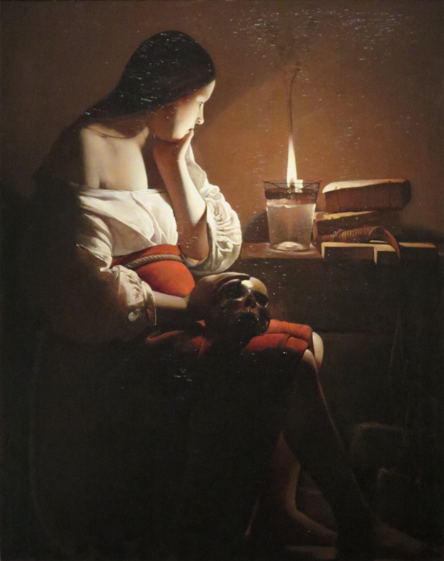Mary Magdalene sitting in candlelight with a skull in her lap