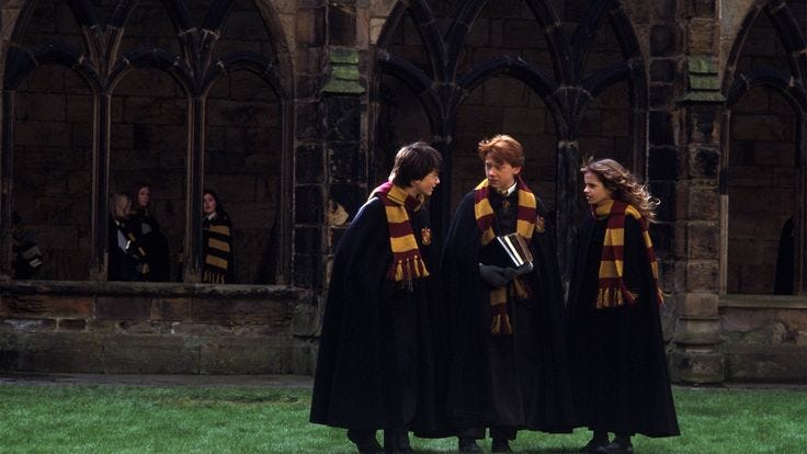 This may contain: three young women dressed in harry potter robes standing outside an old building with people looking on