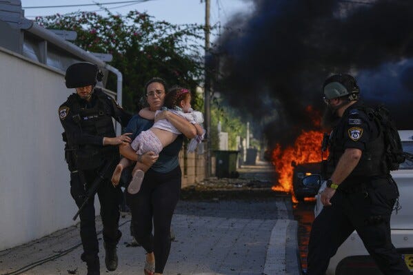 Police officers evacuate a woman and a child from a site hit by a rocket fired from the Gaza Strip, in Ashkelon, southern Israel, Saturday, Oct. 7, 2023. The rockets were fired as Hamas announced a new operation against Israel. (AP Photo/Tsafrir Abayov) Police officers evacuate a woman and a child from a site hit by a rocket fired from the Gaza Strip, in Ashkelon, southern Israel, Saturday, Oct. 7, 2023. The rockets were fired as Hamas announced a new operation against Israel. (AP Photo/Tsafrir Abayov)