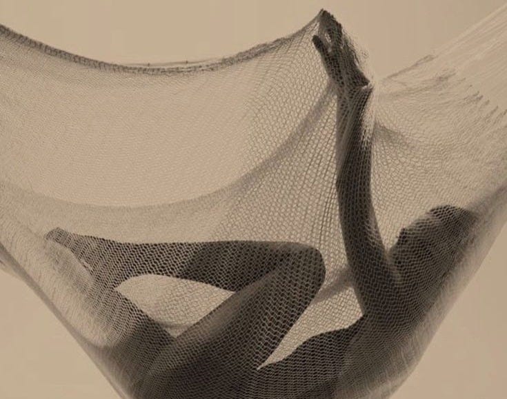 This may contain: a black and white photo of someone laying in a hammock