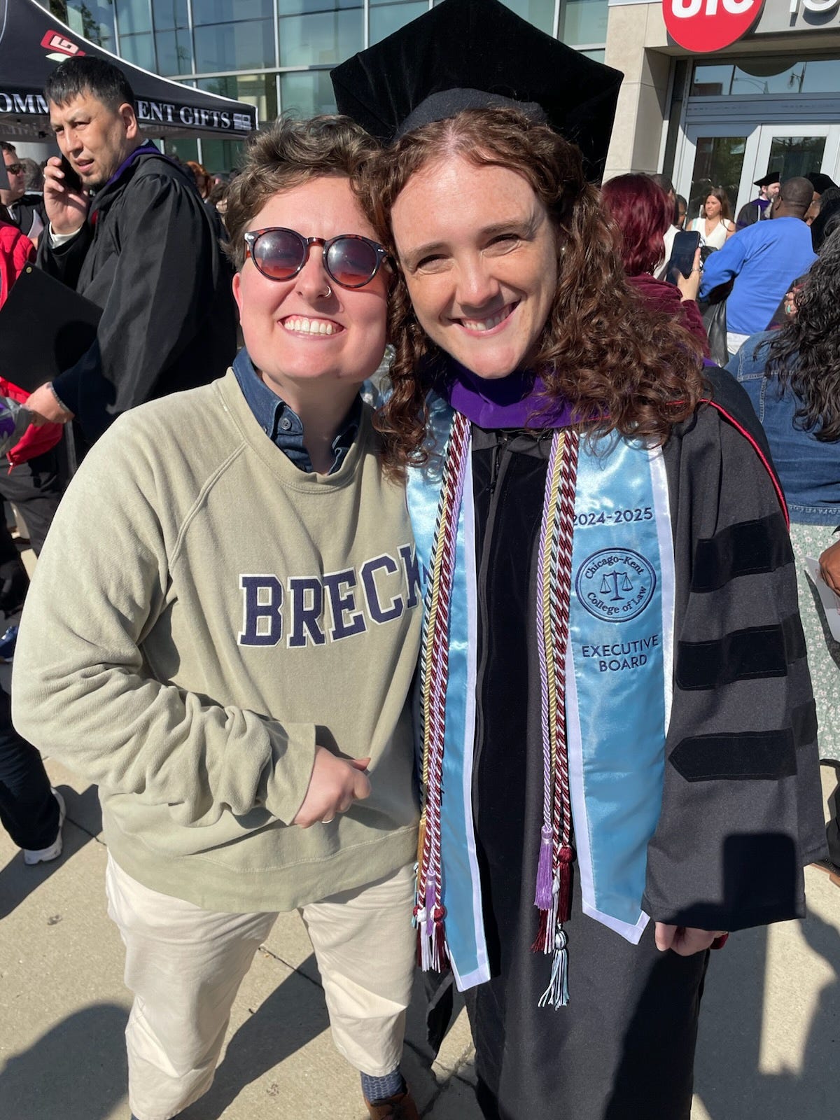 Hannah next to Breck, who is wearing graduation regalia. Hannah is wearing a sweatshirt that says "BRECK."