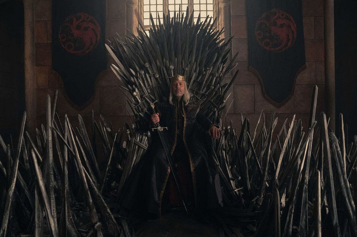 A character from the House of the Dragon sits on the Iron Throne.