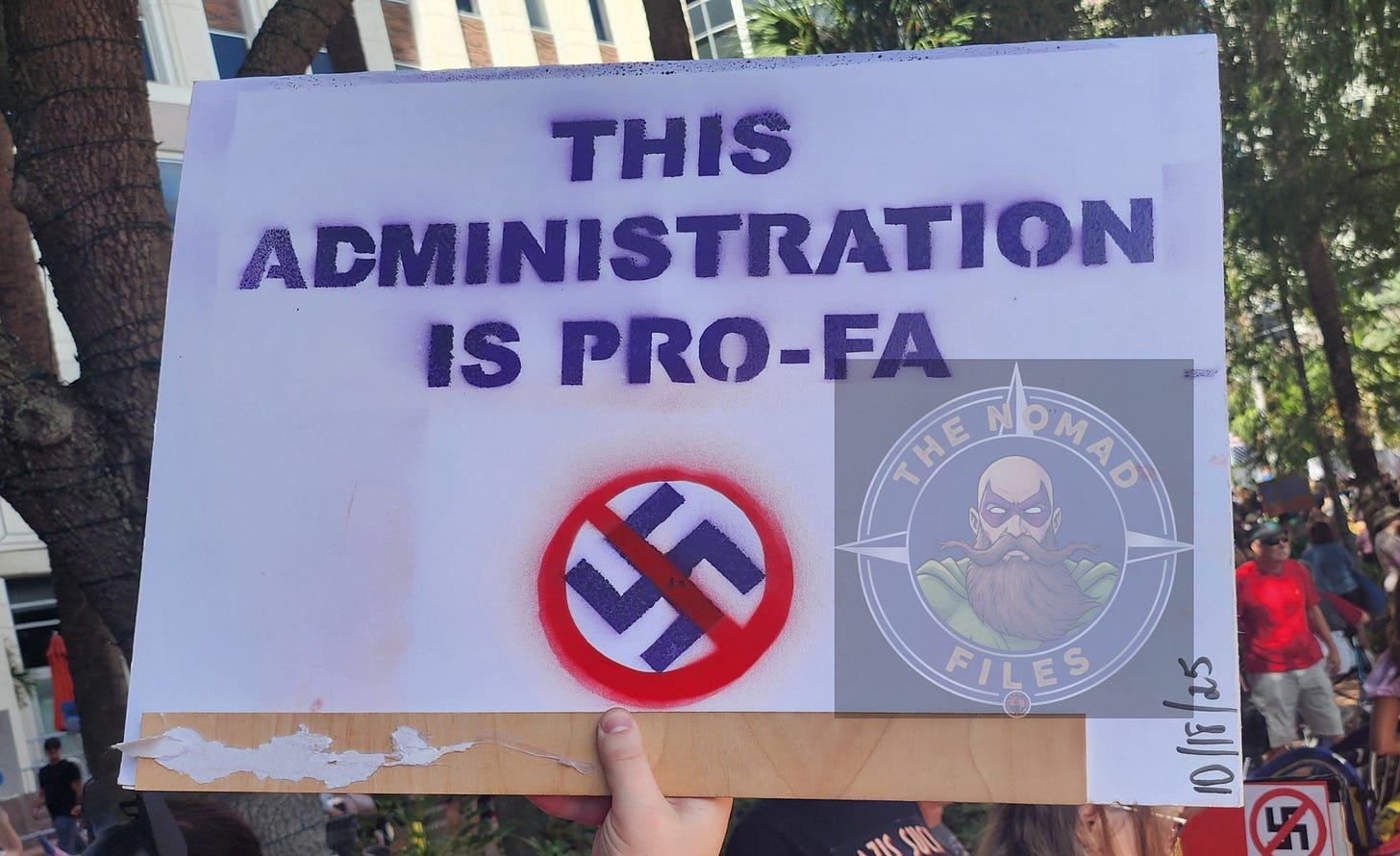 A protest sign with purple stenciled text "THIS ADMINISTRATION IS PRO-FA" above a red crossed-out swastika symbol.