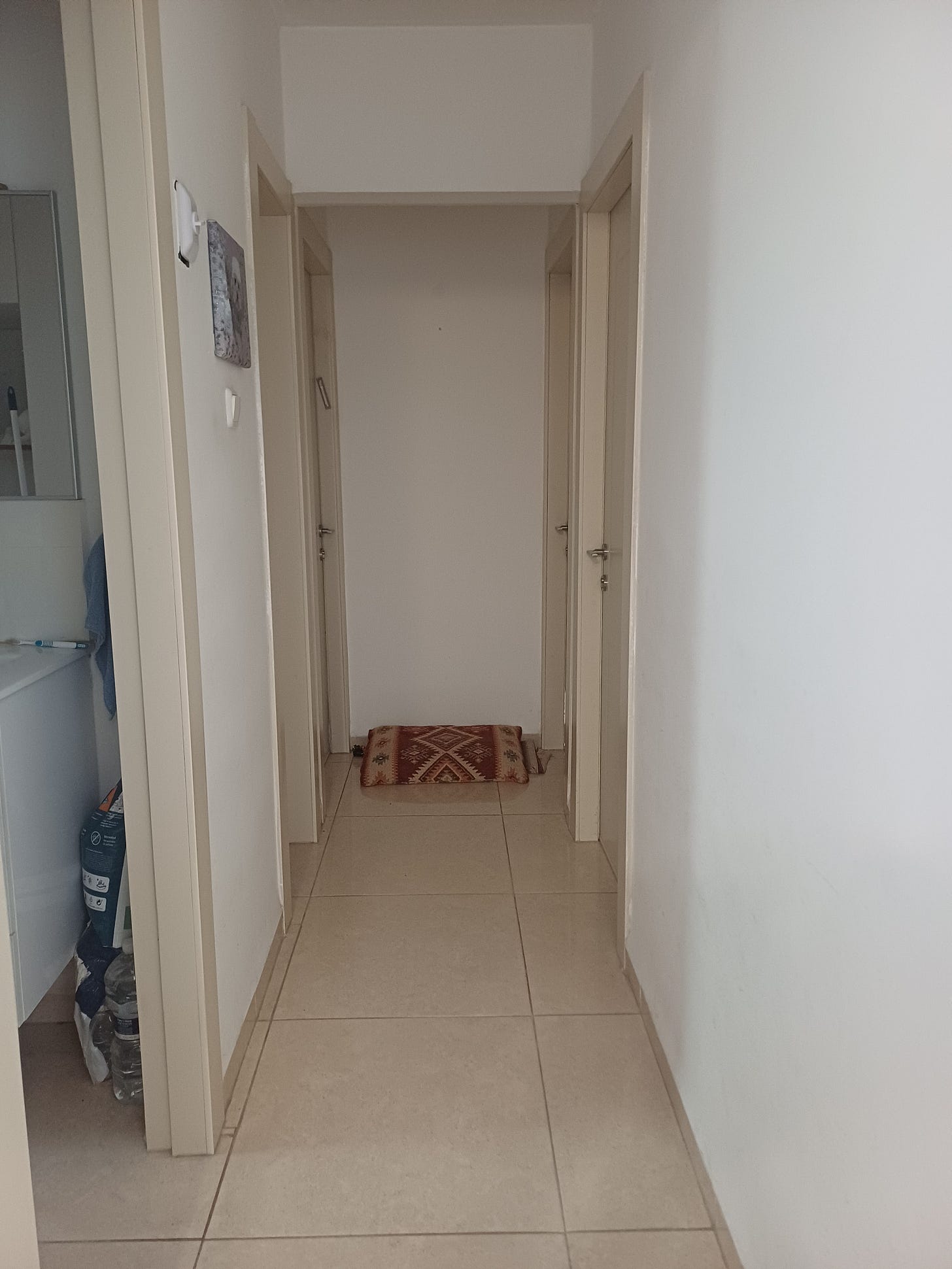 A long hallway with several closed doors, with a pillow at the closed end of the hallway used while waiting 10 minutes after a missile attack A long hallway with several closed doors, with a pillow at the closed end of the hallway used while waiting 10 minutes after a missile attack