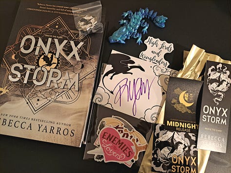 black sweater embroidered with Fourth Wing title and dragon, book, stickers, and signed bookplate for Onyx Storm by Rebecca Yarros
