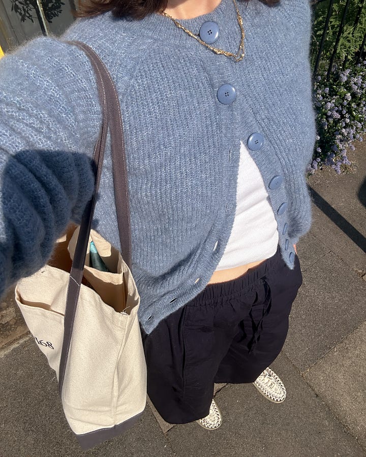 Lucy Moon wears a blue Sezane cardigan, balloon silhouette navy trousers from COS and a Studio 168 tote bag.