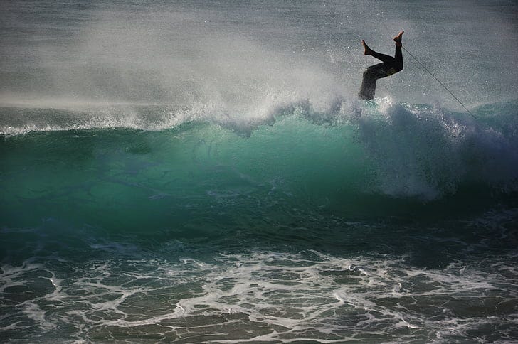 photo of person falling on surfboard in body of water