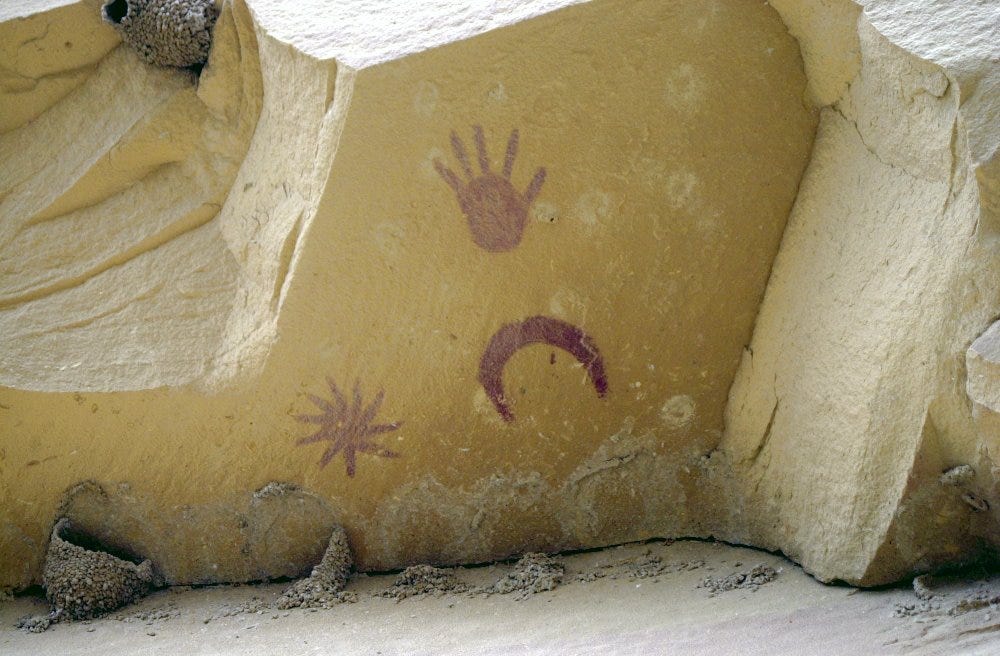 A hand, a crescent moon, and a star painted on a rock face at Chaco Canyon, New Mexico