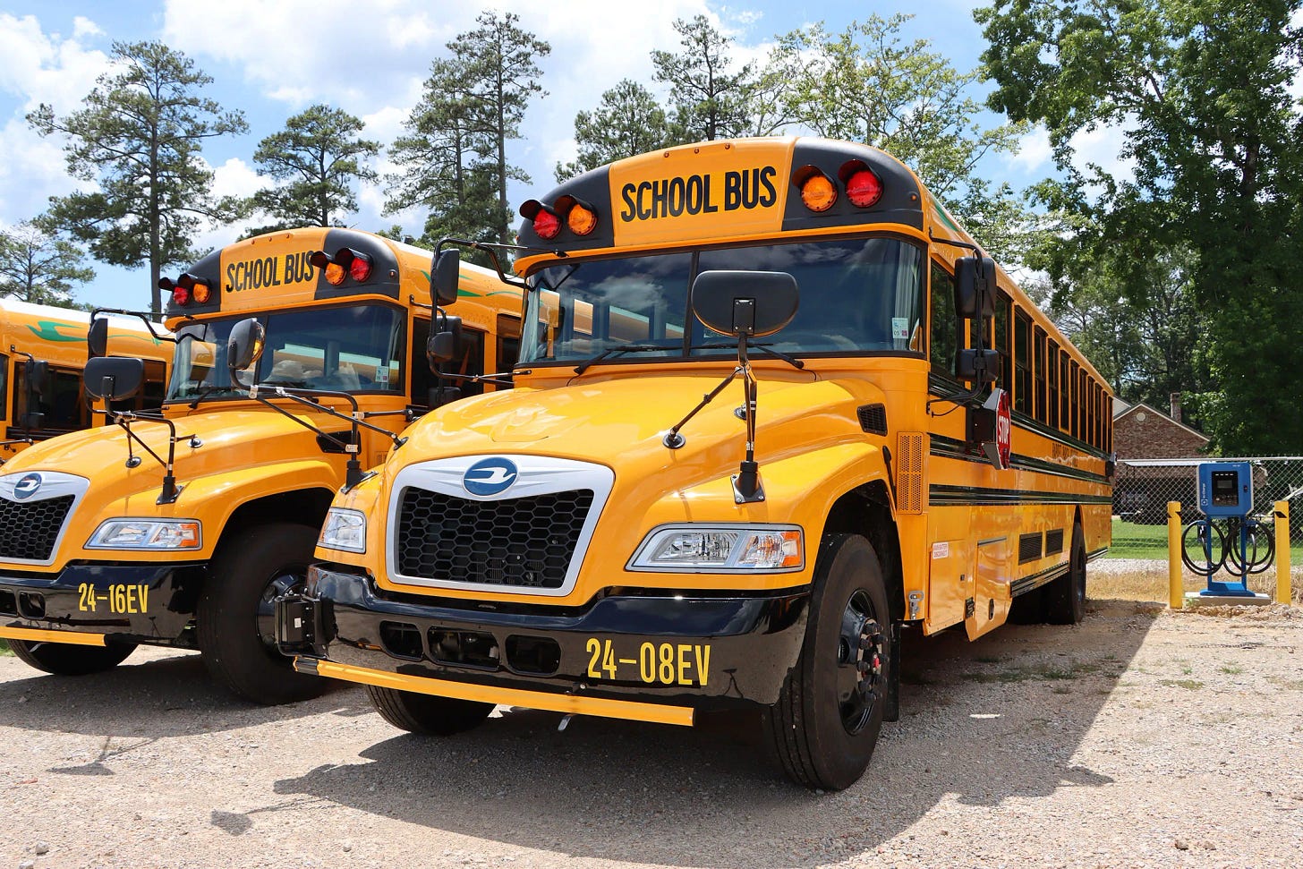 A row of electric buses at Buckeye High School in Rapides Parish, Louisiana next to a charging station A row of electric buses at Buckeye High School in Rapides Parish, Louisiana next to a charging station