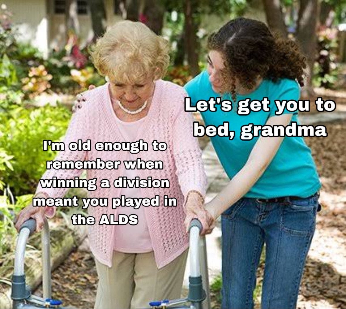 An elderly woman with gray hair wearing a pink sweater and beige pants uses a walker outdoors. A younger woman with curly hair wearing a blue shirt and jeans assists her. Text overlay reads "Let\'s get you to bed, grandma" and "I\'m old enough to remember when winning a division meant you played in the ALDS."