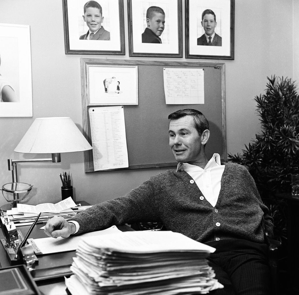 Image may contain Johnny Carson Human Person Furniture Electronics Computer Pc Sitting Table Lamp and Table Lamp