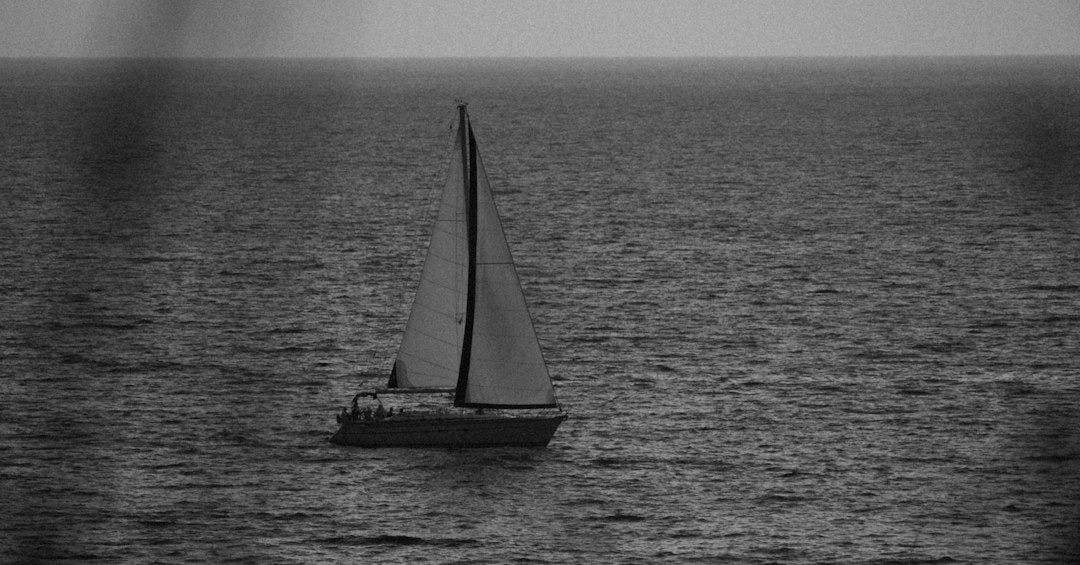 A sailboat in the middle of a body of water A sailboat in the middle of a body of water