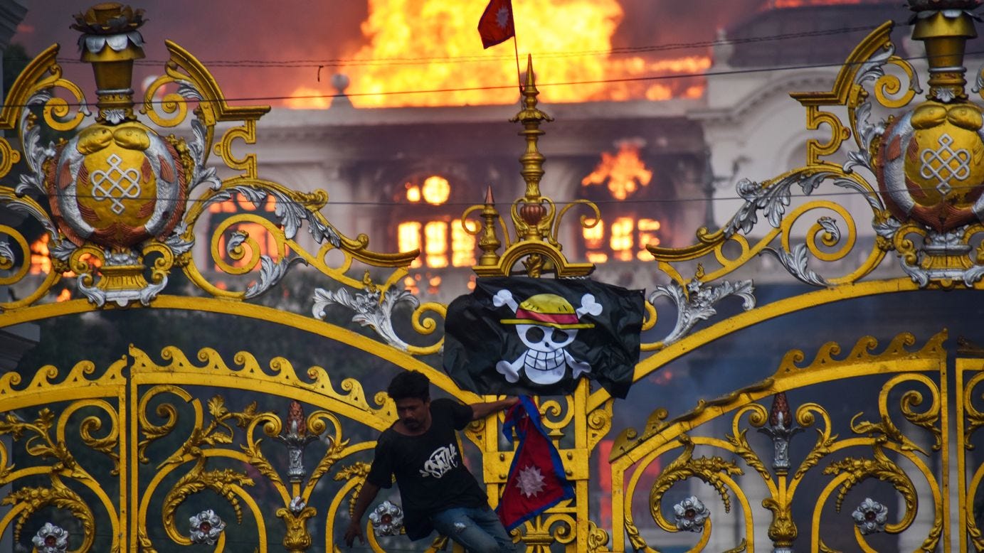 A One Piece flag hangs on the gates of the Singha Durbar palace in Kathmandu, Nepal on September 9 as smoke and flames rise from the building.