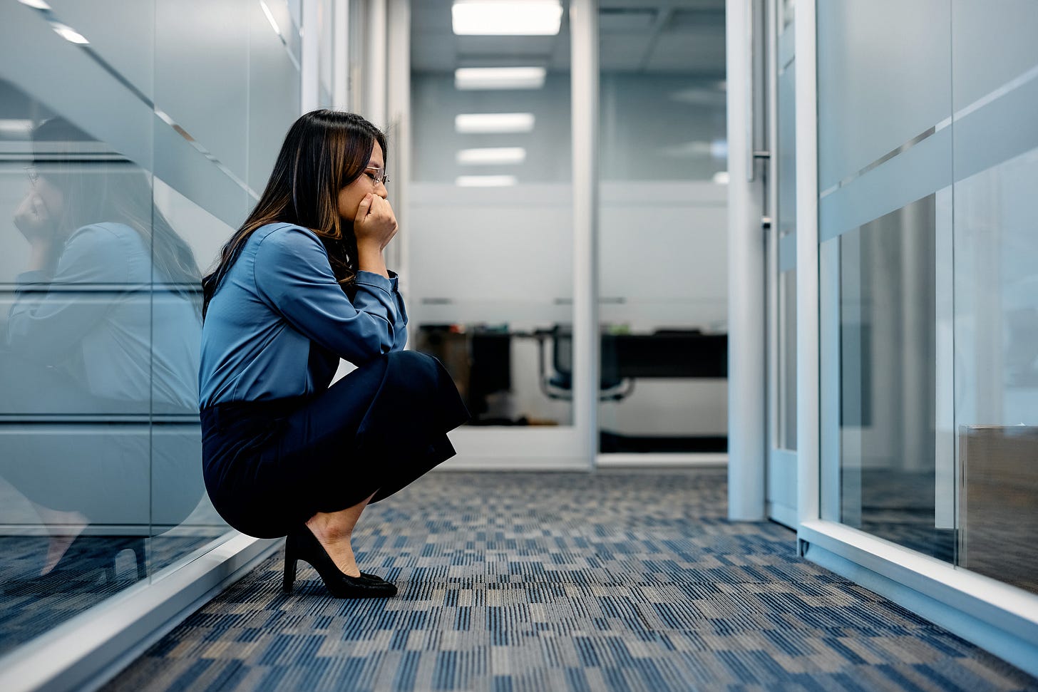 Photo of a young professional crouched in an office hallway
