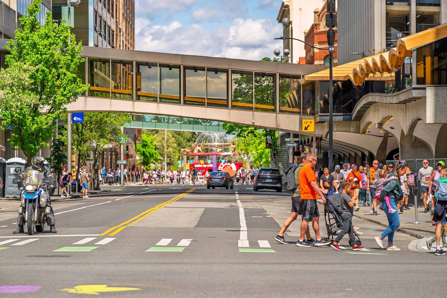 Pedestrians and participants fill the streets of downtown Spokane at the end of the 12K Lilac Bloomsday Run with Riverfront Park in the distance.