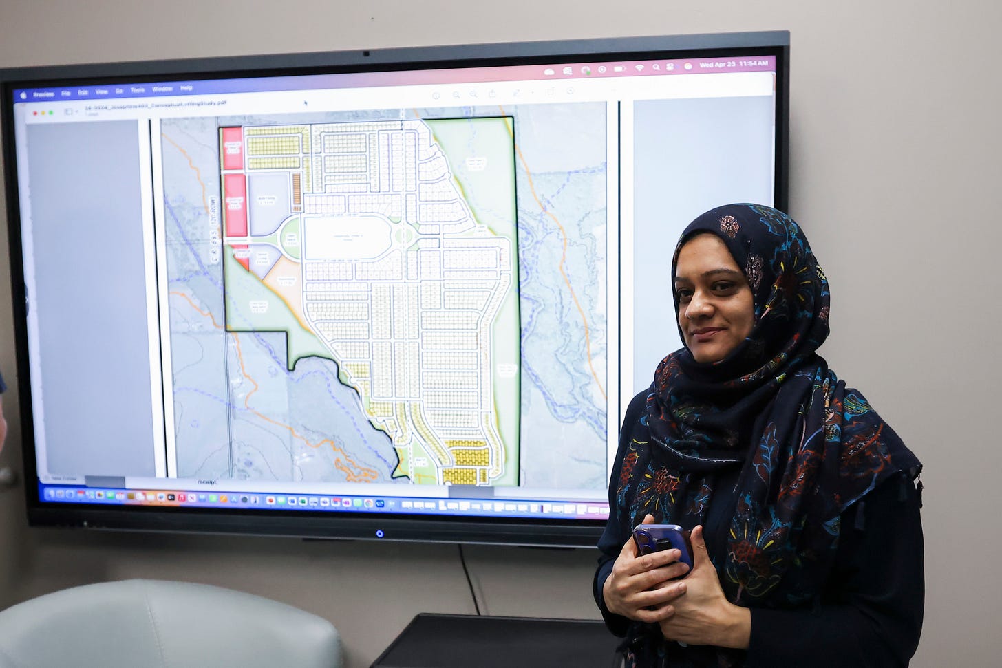 Planolainen Fawzia Belal seisoo Epic Cityn tulevan kehityksen projektion vieressä. Planolainen Fawzia Belal seisoo Epic Cityn tulevan kehityksen projektion vieressä.