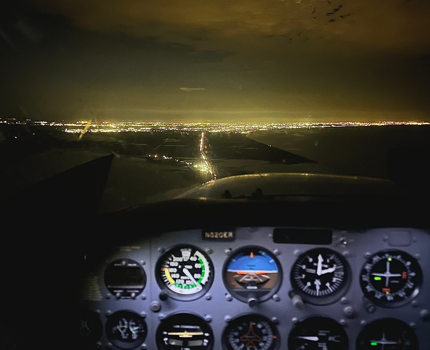 an image of an airport at night from the cockpit of the plane, which contains dials and knobs an image of an airport at night from the cockpit of the plane, which contains dials and knobs