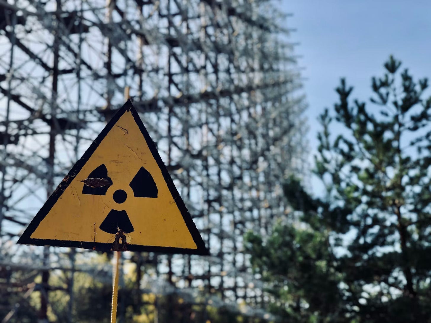 A weathered nuclear radiation sign near a scaffold