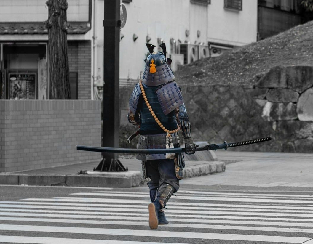 man in blue and black suit holding black rifle walking on pedestrian lane during daytime